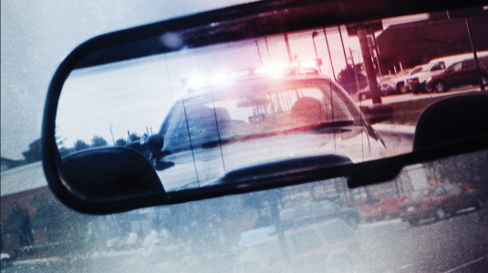 Police car seen through rearview mirror