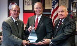 Sheriff Jimmy Abbett of Tallapoosa County (left) and Chief R. Alan Benefield (right), executive secretary of the Alabama Peace Officers Standards and Training Commission, present President Don Killingsworth a plaque honoring the police academy’s 50th anniversary.
