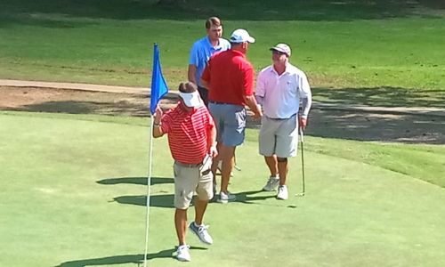 Ty Cole (right) and Gary Wigington shake hands as Tee Brown looks on and Jeremy McGatha replaces the flag after completing Sunday’s final round of the Etowah County Open on the Links at Briarmeade. Cole won by one stroke. (Photo by Joe Medley)