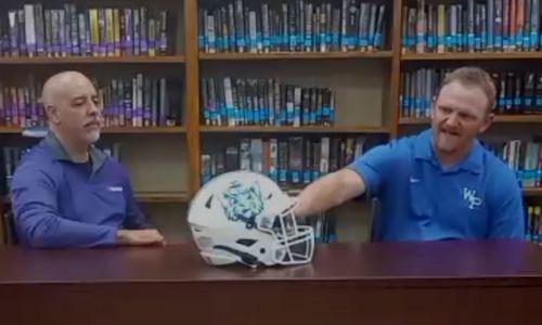 White Plains coach Blake Jennings shows off the Wildcats’ new helmet during Wednesday’s preseason interview at the school. (Photo by Joe Medley)