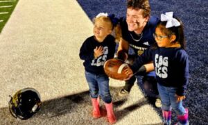 Jacksonville quarterback Jim Ogle holds the football commemorating his 100th career touchdown pass Friday with Emersyn Edwards (left) and Madi Smith. (Photo by Joe Medley)