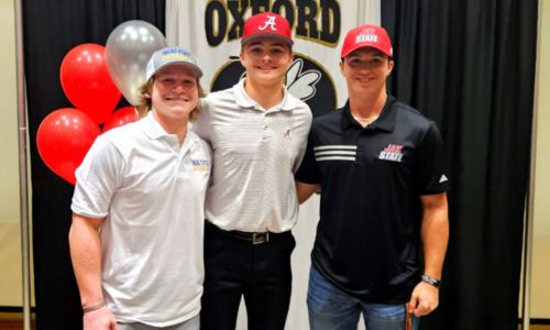 Oxford seniors (from left) Forrest Heacock, Carter Johnson and R.J. Brooks sport the caps of their college choices during Friday’s signing ceremony in the school’s media center. (Photo by Joe Medley)