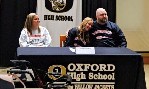 Oxford’s Reagan Sanders gets a hug from her father, Jeremy, as her mom, Jenny, looks on during Monday’s signing ceremony in the school’s media center. (Photo by Joe Medley)