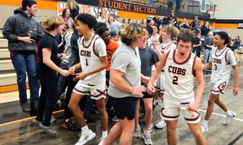 Alexandria’s Cleat Forrest (2), Drake Davis (1), Chris Aquirre (3) and teammates celebrate with the student section after beating rival Jacksonville 74-71 on Thursday. (Photo by Joe Medley)