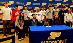 Piedmont’s Claudia Dempsey (seated, center) poses with her parents and teammates during Monday’s ceremony to mark signings for three Piedmont athletes. (Photo by Joe Medley)