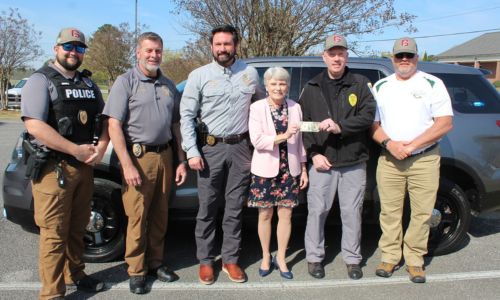 : Dr. Kathy Murphy, president of Gadsden State, presents a dollar to Hokes Bluff Chief of Police Tyler Roe in exchange for a fully-equipped Ford Explorer. Joining them are, from left, Sgt. Colton Harden, Sgt. David Bankson and Chief Jay Freeman, all of the Gadsden State Police and Public Safety Department, and Hokes Bluff Mayor Scott Reeves.