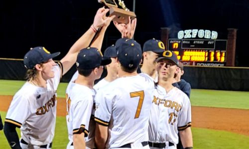 Judd Syer (right) and his Oxford teammates hoist the Calhoun County championship trophy Thursday after the Yellow Jackets beat Alexandria 3-2 in 11 innings at Choccolocco Park. (Photo by Joe Medley)