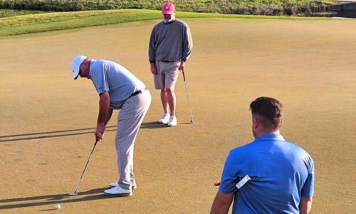 With teammate Ty Cole (center) looking on, Gary Wigington putts to finish off their 12-under-par round during Saturday’s first round of the Calhoun County Team Championship at Silver Lakes. (Photo by Joe Medley