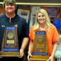 Alexandria baseball coach Zac Welch holds the 2024 state-title trophy he and his team earned, and wife Whitney Welch holds the 2017 state-title trophy that she and her volleyball team earned. (Photo by Joe Medley)