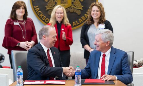 Jacksonville State University President Dr. Don C. Killingsworth, Jr., left, and Regional Medical Center President and CEO Louis Bass, right, shake hands after signing a memorandum of understanding that allows eligible RMC employees to receive a 20% tuition scholarship for continuing their education. (JSU Photo)