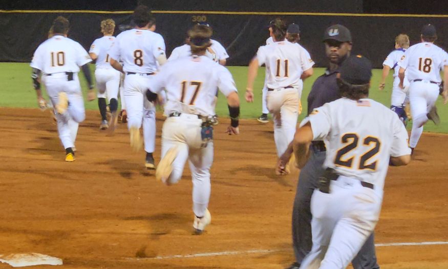 Choccolocco Monsters players charge the field after Jake Goolsby after he delivered a game-winning single against the Sunbelt League-leading Gainesville GolDiggers on Friday at Choccolocco Park. (Photo by Joe Medley)