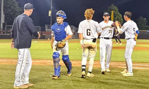Choccolocco Monsters coach Ricky Ray Clayton (left) greets catcher Tate Morris while Cole Tremain (6) and Mason Walker (5) greet pitcher Thomas Ballard during their 5-1 victory over the Gainesville GolDiggers on Saturday at Choccolocco Park. (Photo by Joe Medley)