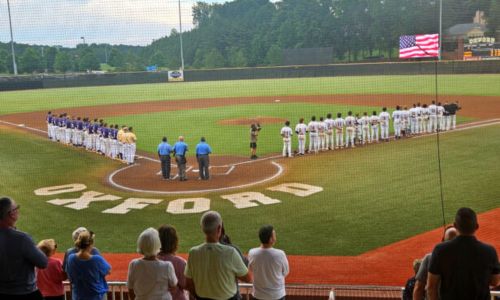 A day after Independence Day, the Choccolocco Monsters (right) and Cartersville Cannons line up for the National Anthem before their game Friday at Choccolocco Park. (Photo by Joe Medley)