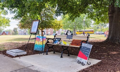 Artwork, flowers, photos, and mementos surround the plaque and bench that were dedicated to the memory of student Leah Grace Tarvin, who passed away in November 2022. (JSU Photo)