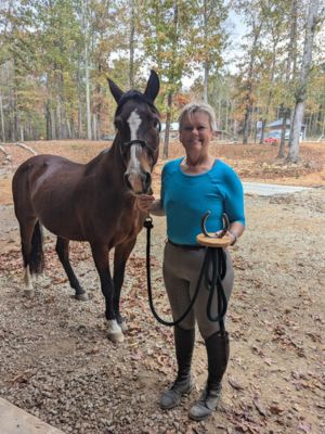 Vicki Ashley photographed with her 19-year-old horse, Cinco, showcasing her first place trophy.