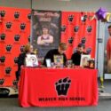 Weaver’s Brandon Jolliff puts pen to paper Wednesday as Weaver coach Andy Fulmer watches in the school library. (Photo by Joe Medley/East Alabama Sports Today)