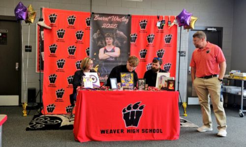 Weaver’s Brandon Jolliff puts pen to paper Wednesday as Weaver coach Andy Fulmer watches in the school library. (Photo by Joe Medley/East Alabama Sports Today)