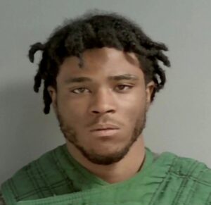 photo of Tori Dimming after arrest. Black Male with medium black hair and slight beard wearing green shirt