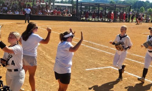 Oxford coach Wendy McKibbin greets players coming to the dugout between innings during the Yellow Jackets’ state-tournament game against Saraland on Monday at Choccolocco Park. (Photo by Joe Medley/East Alabama Sports Today)